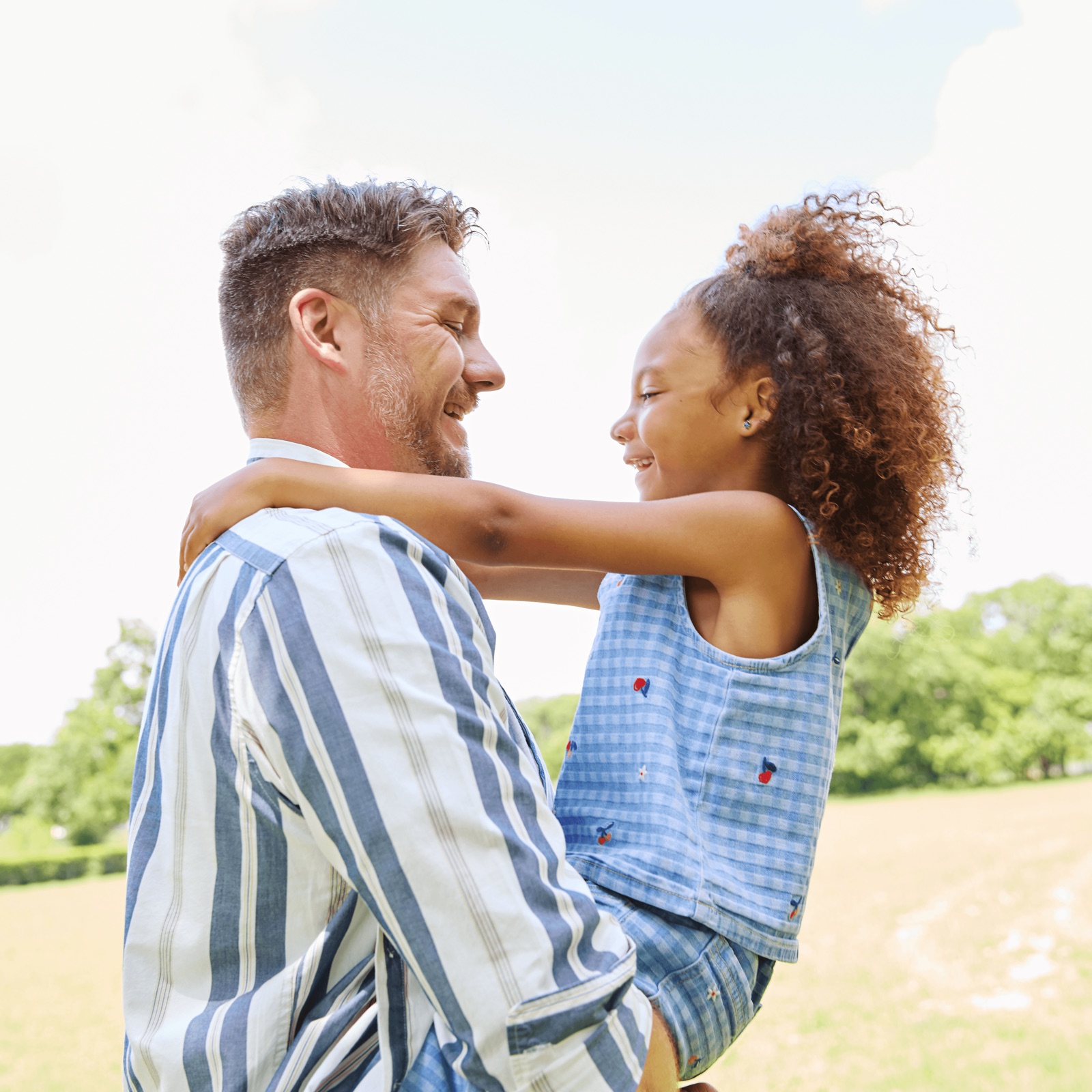 A father lifting his daughter in a park