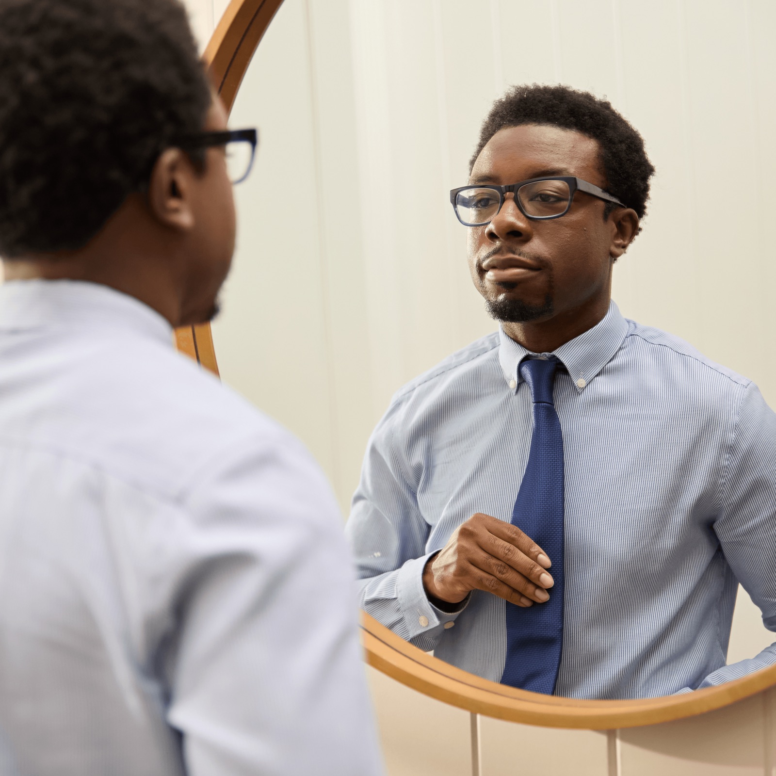 A man adjusting his tie in a mirror before an interview